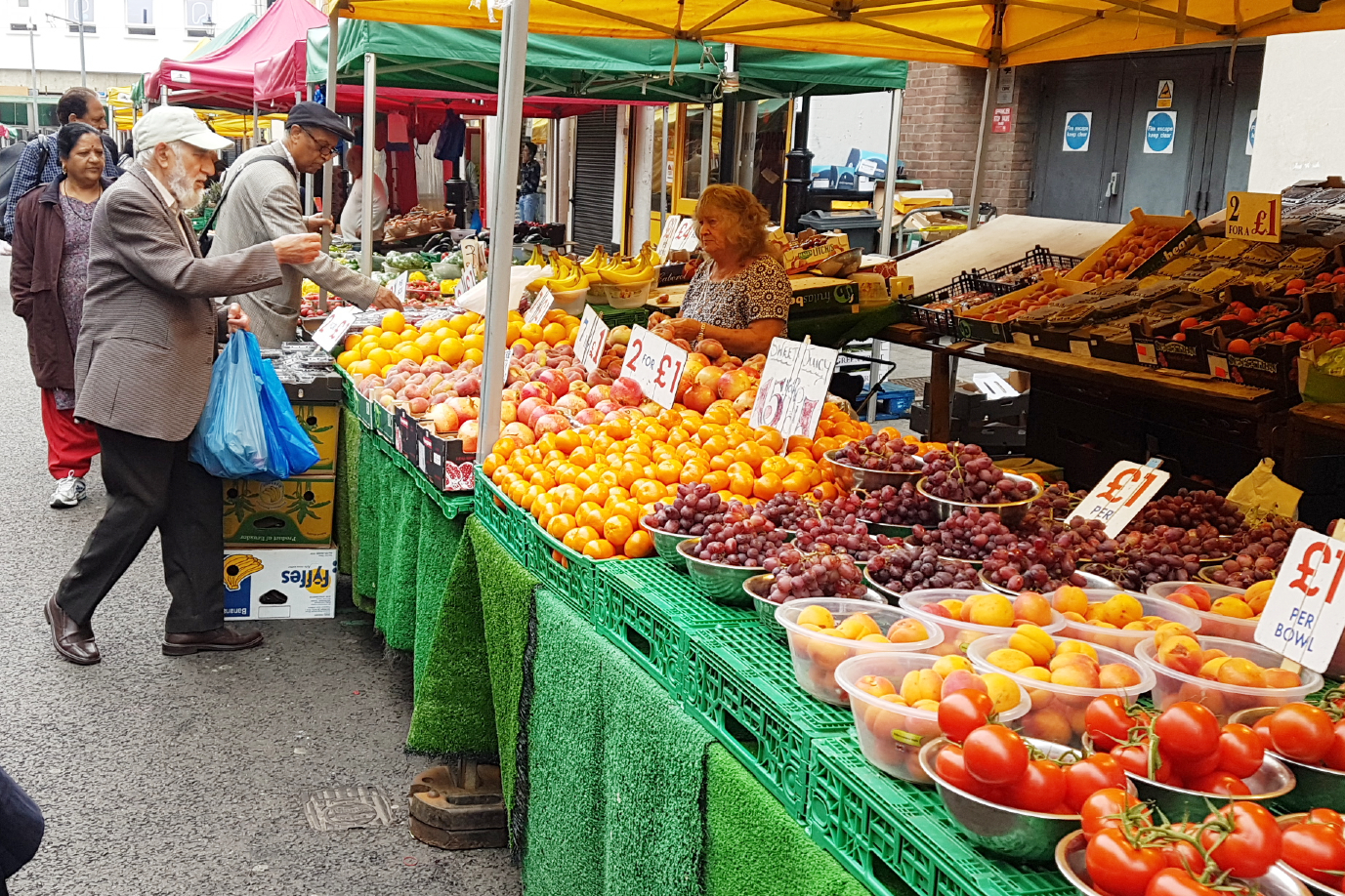 People browsing and buying fruit from a street market stall